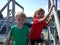 Boy and girl posing on a pier. Red and green t-shirts without patterns. Children play near metal structures in the port. Ships and