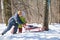 Boy and girl push sledge in winter in wood