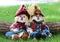 Boy and girl scarecrows sitting on grass by log next to a lake