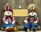 Boy and girl scarecrows sitting on log by pumpkin and blank wood sign