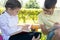 A boy and a girl in school uniform do their homework while sitting in a park on the road on a warm autumn day