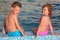 Boy and girl sit on border of pool