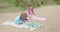 Boy and girl sitting on beach towels, little girl eating a cookie