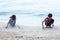 Boy and girl sitting and writing the SOS sign on the sandy beach while going on vacation to the sea.