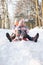 Boy And Girl Sledging Through Snowy Woodland