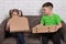 Boy and girl on sofa, holding pizza boxes, smiling and peeking into the box