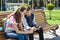 Boy and girl teenagers play, read, look at the smartphone. On the bench, the urban background