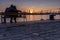 Boy and girl watches the sunset at the sea station with ships.