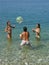 Boy and girls playing with ball on sea