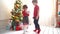 Boy gives a girl a Christmas present near a christmas tree in a bright sunny room