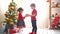 Boy gives a girl a Christmas present near a christmas tree in a bright sunny room