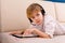 A boy with glasses and headphones is learning lessons with a tablet and books. Home distance learning online