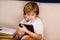 A boy with glasses and headphones is learning lessons with a tablet and books. Home distance learning online