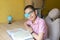 Boy in glasses with patch studying homework with book. Quarantine. Distance learning. Remote education. Treat lazy eye, amblyopia/