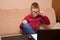 A boy in glasses and a red shirt sits at a black table and does homework, a child in quarantine on distance learning. he