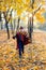 boy in glasses runs in autumn park with gold leaves, holds book in his hands