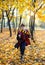 Boy in glasses runs in autumn park with gold leaves, holds book in his hands, wears in black robe