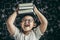 A boy with glasses studied and put a book on his head in the classroom