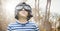 Boy with goggles against blurry trees with flare