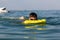 A boy in goggles learns to swim with a yellow inflatable mattress. Teenager swims in the sea with big splashes.