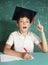 Boy in graduation cap on the blackboard background close up portrait