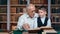 Boy grandchild and elderly professor grandfather talking scientific exploration reading textbook