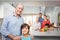 Boy with grandfather while family by kitchen table in background