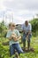 Boy With Grandfather Gardening In Allotment