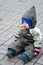 A boy in green snowsuit sitting on paving stone
