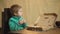 Boy in a green sweater eats a pizza while sitting on a wooden chair. Tasty pizza. Little boy holds slice of pizza