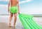 Boy with green swimming mattress stands on seasurf line