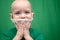 Boy in a green T-shirt on a green background in a mask on his face, smiles takes off the mask recovered