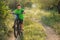 A boy in a green T-shirt starts cycling, in nature, surrounded by greenery, beautiful sunlight