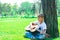 A boy with a guitar sits under a tree, sings songs and enjoys nature