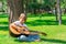 A boy with a guitar sits under a tree, sings songs and enjoys nature