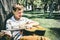 A boy with a guitar under a tree, a teenager plays and sings in