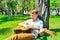 A boy with a guitar under a tree, a teenager plays and sings in the park