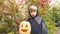 Boy in Halloween costume holding pumpkin jack-o-lantern, alone in forest, spooky