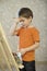 Boy With Hand On Forehead Standing In Front Of Easel