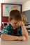 Boy with hand on head sleeping in a classroom