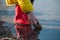 Boy hand playing with pebbles in the lake water wearing rubber boots