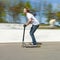 Boy has fun jumping with the push scooter at the skate park