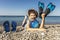 Boy has water polo ball and scuba gear on the beach. Looking at camera. Concept of travel, tourism, family