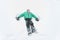 Boy in hat, scarf and green jacket lying in snow and making angel. Portrait. Close-up. Winter day