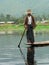 Boy in hat standing in wooden boat with reflection, Inle Lake, Burma