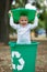 Boy have fun inside recyling waste bin outside. Concept of environmental protection. Colorful boxes.