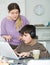 Boy in headphones playing at laptop and  having quarrel with mother