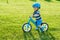 Boy in helmet riding a blue balance bike run bike