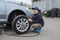 The boy helps at a car service. Replacing the wheels on the car, the jack holds the body in a raised position, with the wheel