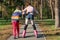 The boy helps the girl to roller-skate in the park. Brother supp